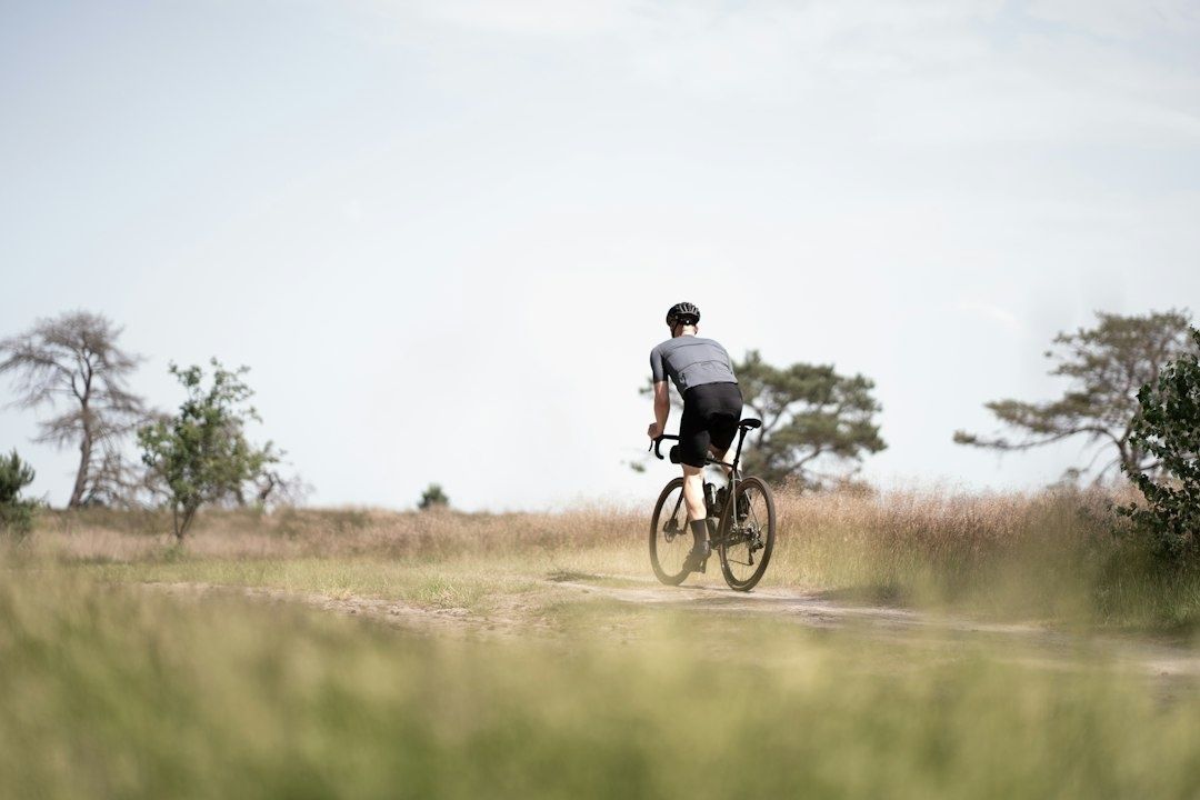 Gravelfietser rijdt over een onverharde heideweg in een open landschap
